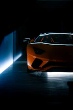 A sleek sports car silhouette glowing with saffron orange accents against a dark charcoal background.