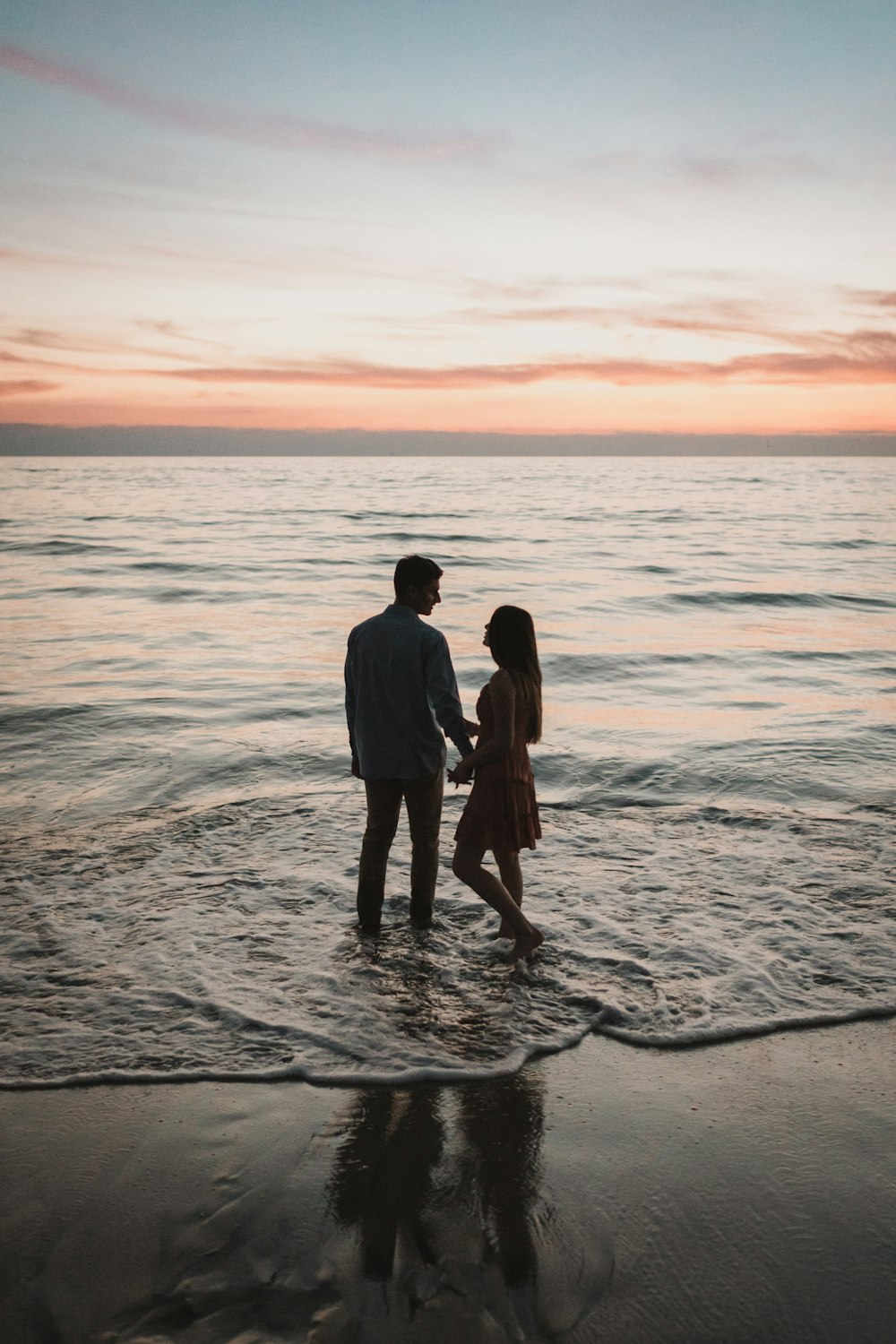 Un uomo e una donna in piedi nell'oceano al tramonto