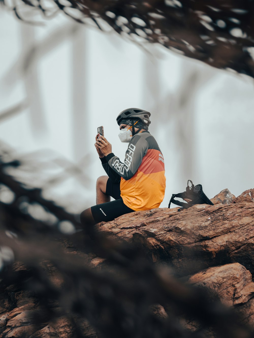 a man sitting on top of a rock while holding a cell phone