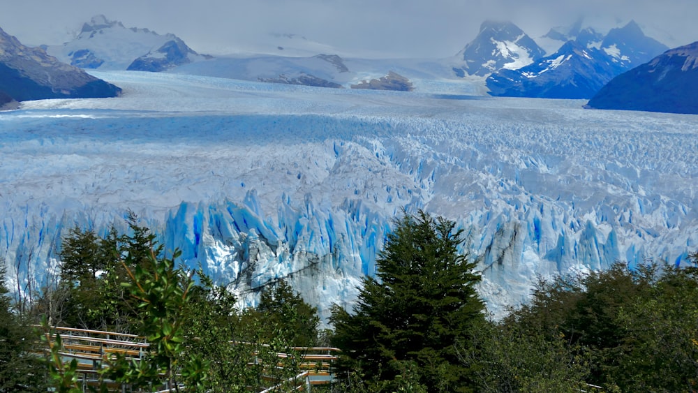 a large glacier with mountains in the background
