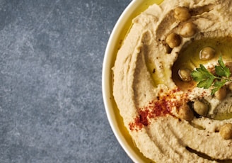 a white bowl filled with hummus and olives