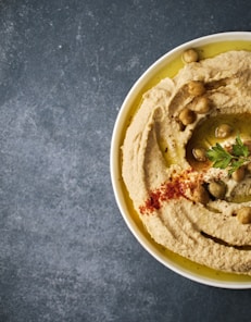 a white bowl filled with hummus and olives