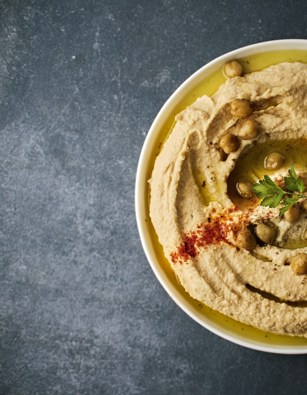 eine weiße Schüssel gefüllt mit Hummus und Oliven