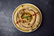 a bowl of hummus with a garnish on top