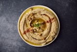 a bowl of hummus with a garnish on top