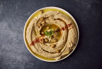 a bowl of hummus with a garnish on top