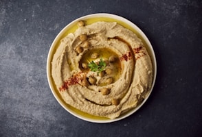 a bowl of hummus with a garnish on top