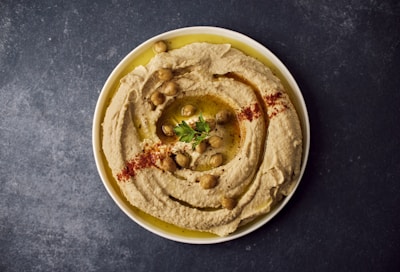 a bowl of hummus with a garnish on top