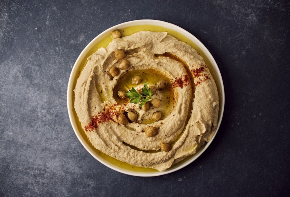 a bowl of hummus with a garnish on top