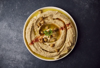 A bowl of hummus with garnish, representing an international and pan-African dining spread at a safari lodge