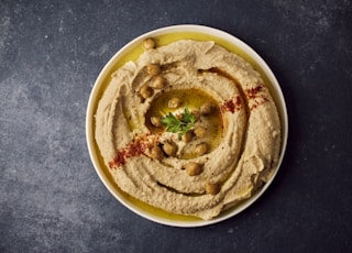a bowl of hummus with a garnish on top