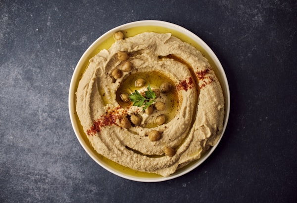 A bowl of hummus with a garnish on top
