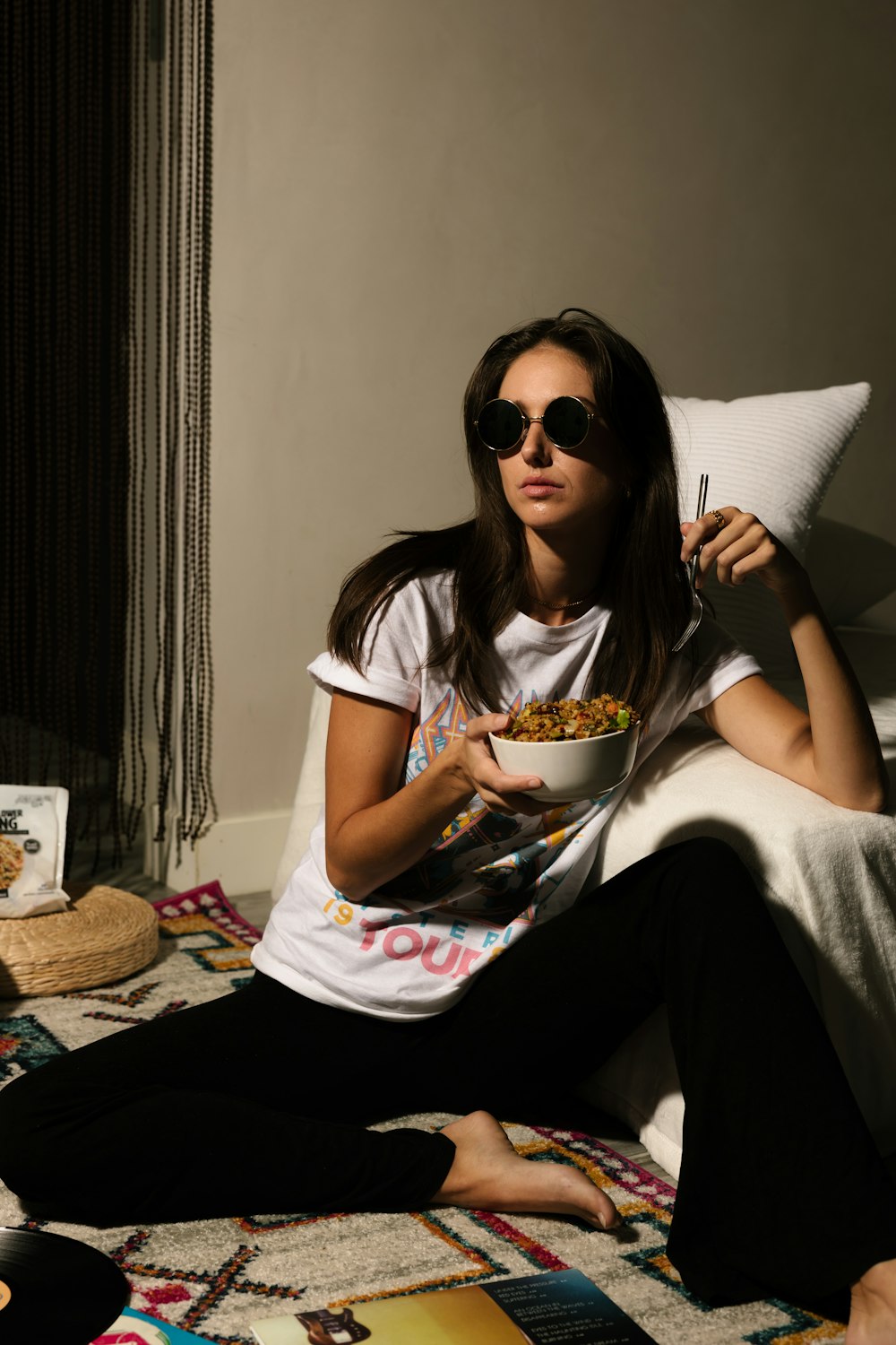 a woman sitting on a bed eating a bowl of cereal