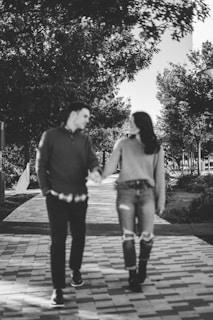 a man and a woman walking down a sidewalk holding hands