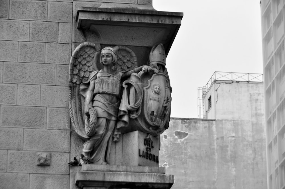 a black and white photo of a statue on a building