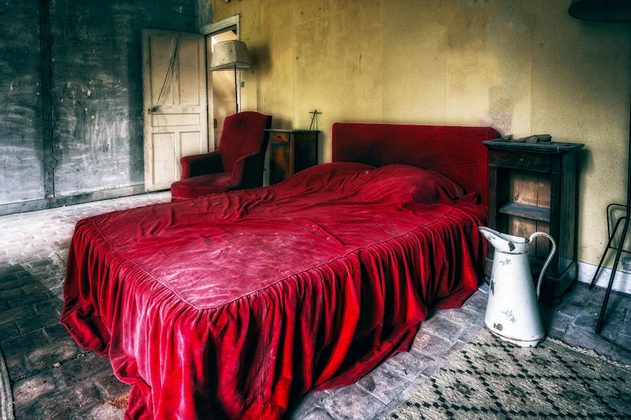 Chambre Berbère — lit drapé de couvertures rouges traditionnelles