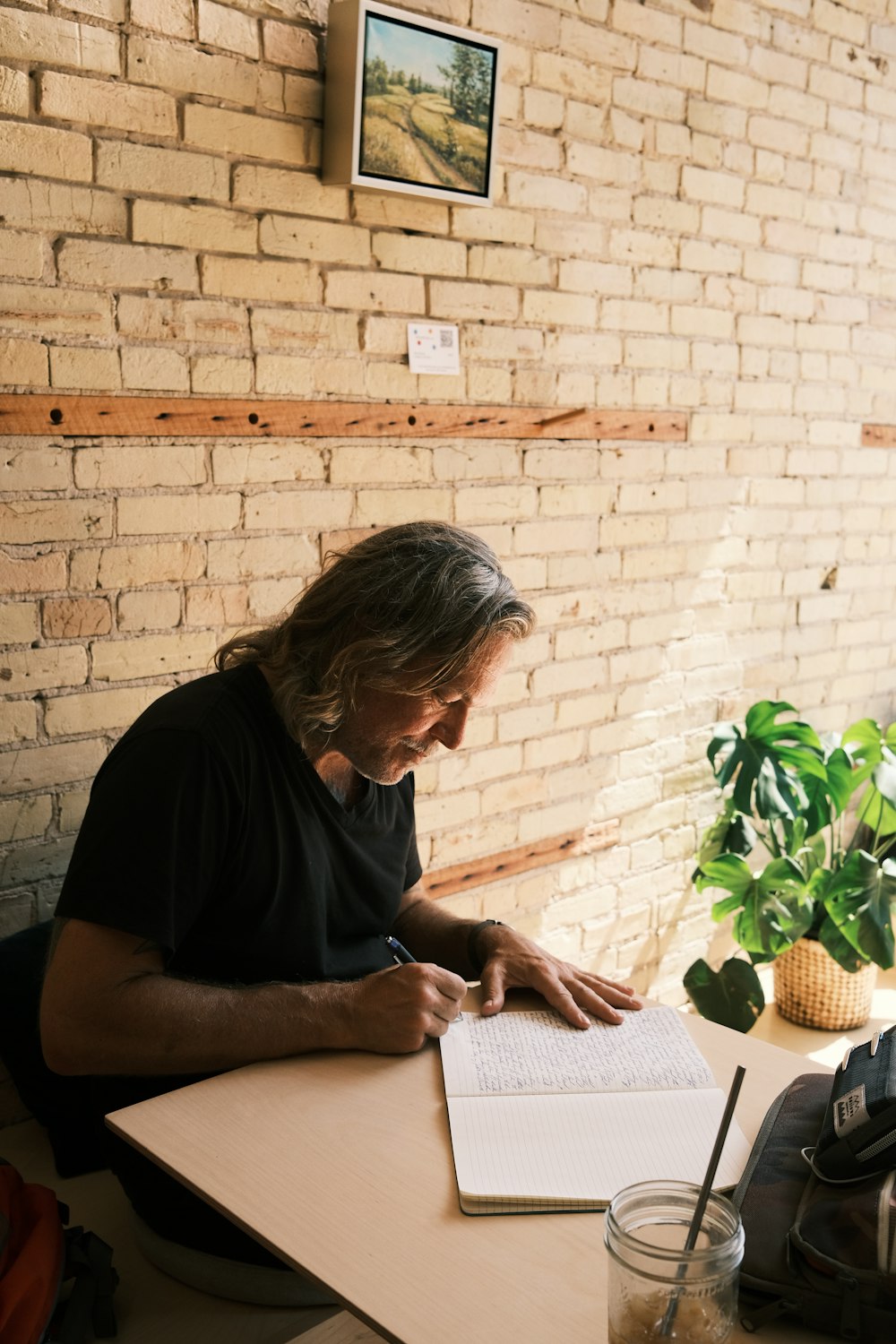 a man sitting at a table writing on a notebook