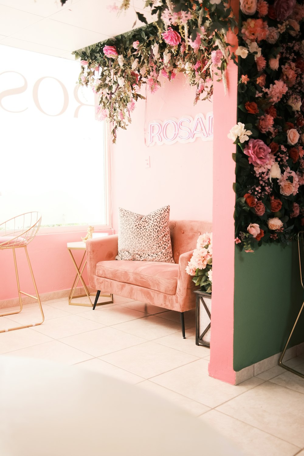 a room with a pink couch and flowers on the wall