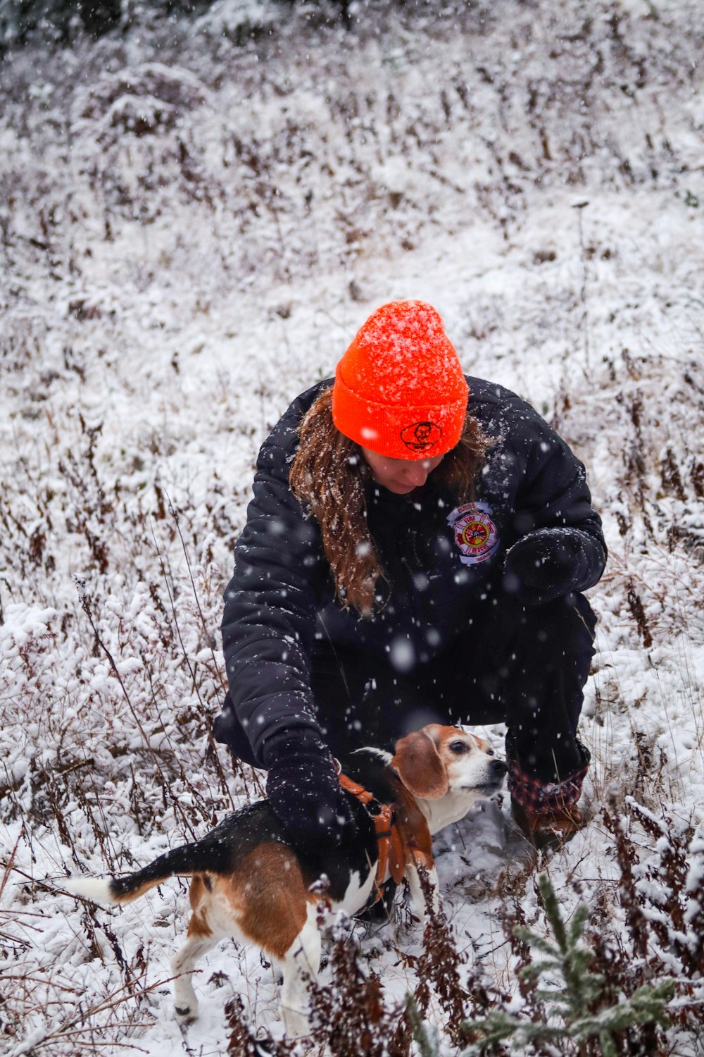 a woman kneeling in the snow with two dogs