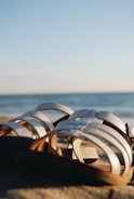 A stylish pair of sandals displayed on a sandy beach with waves in the distance.