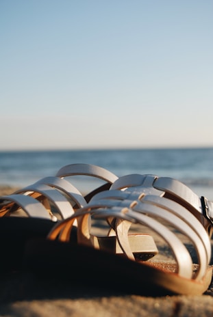 A pair of elegant summer sandals on a sandy beach.