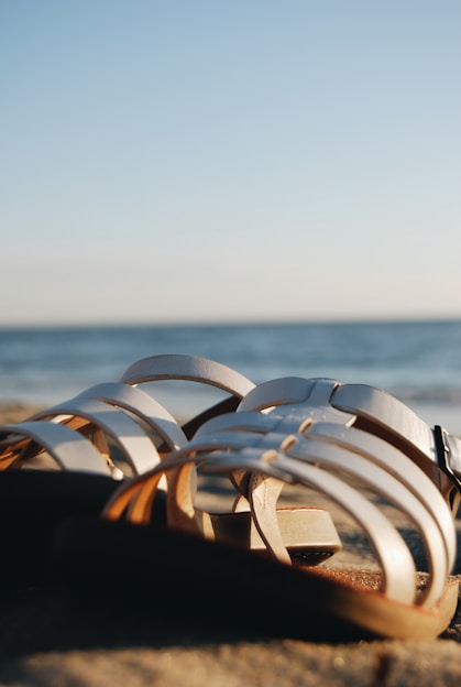 A pair of stylish sandals on a sandy beach.