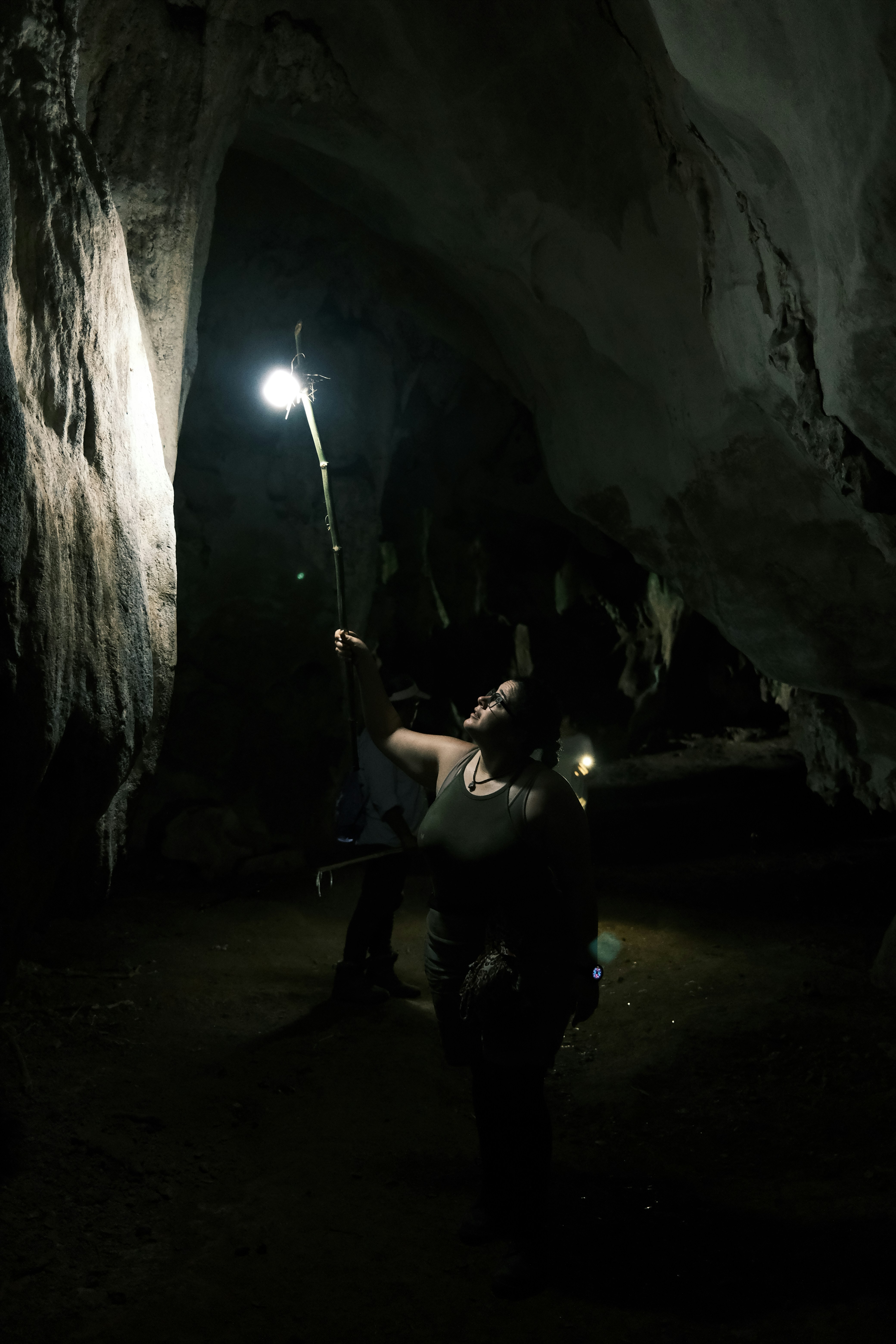 a woman holding a flashlight in a cave