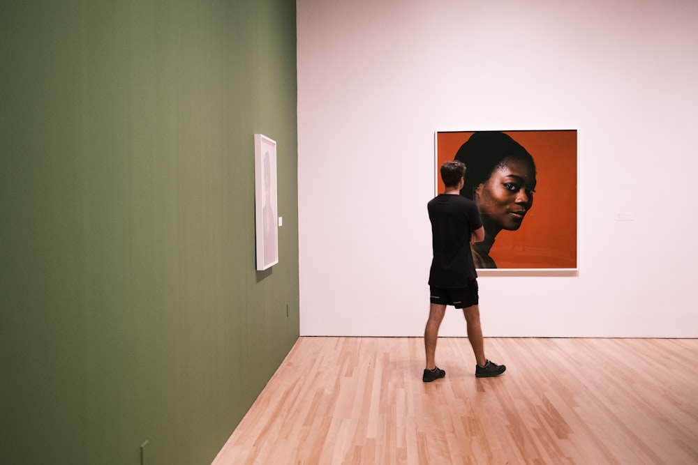 a person standing in a room with a painting on the wall