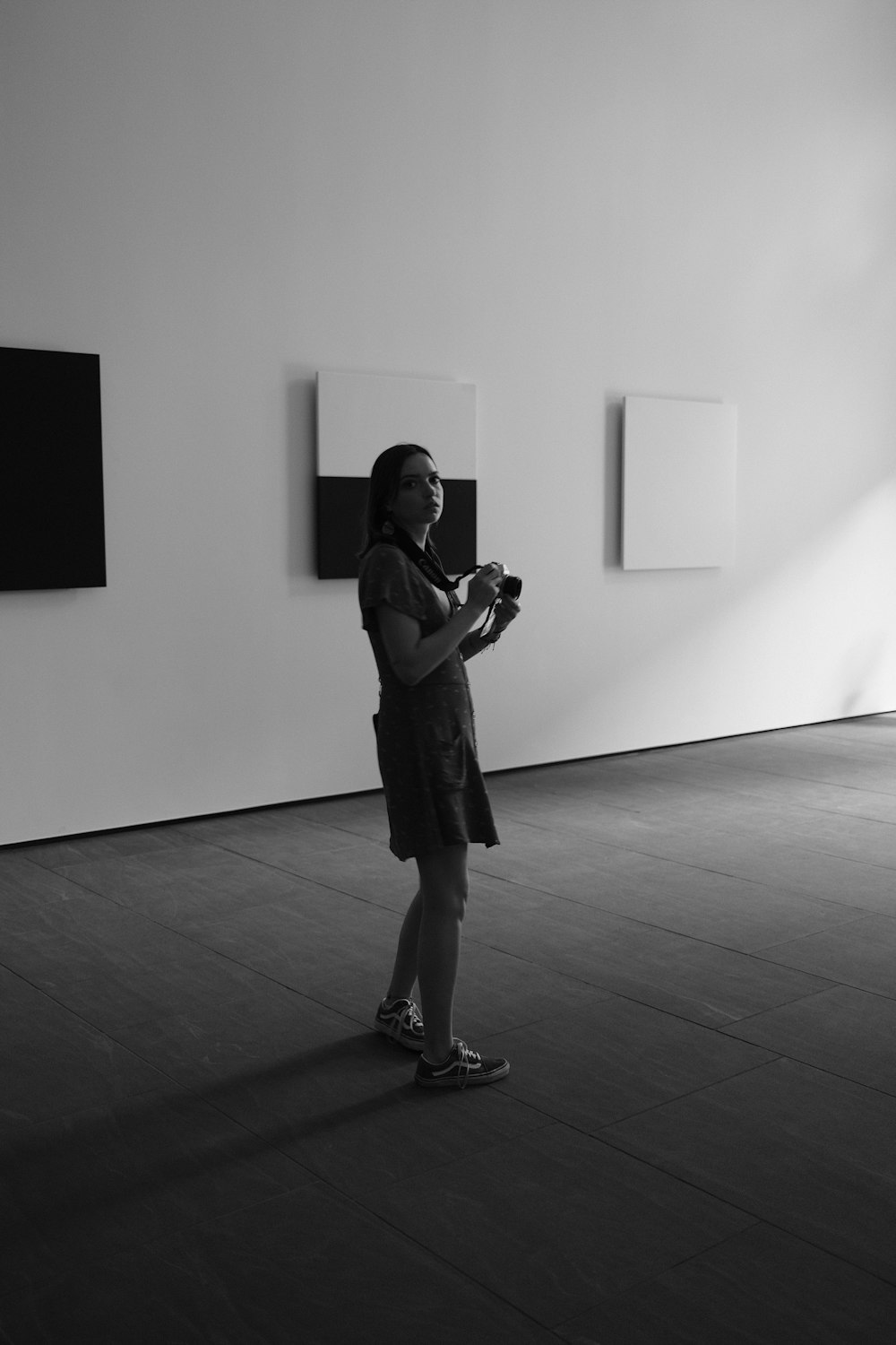 a woman standing in a room with paintings on the wall