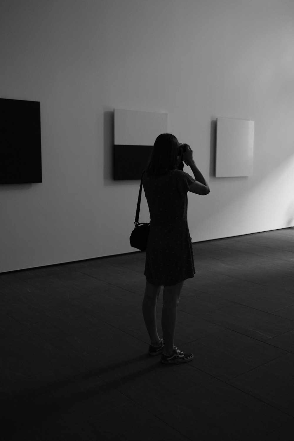 a woman taking a picture of some paintings