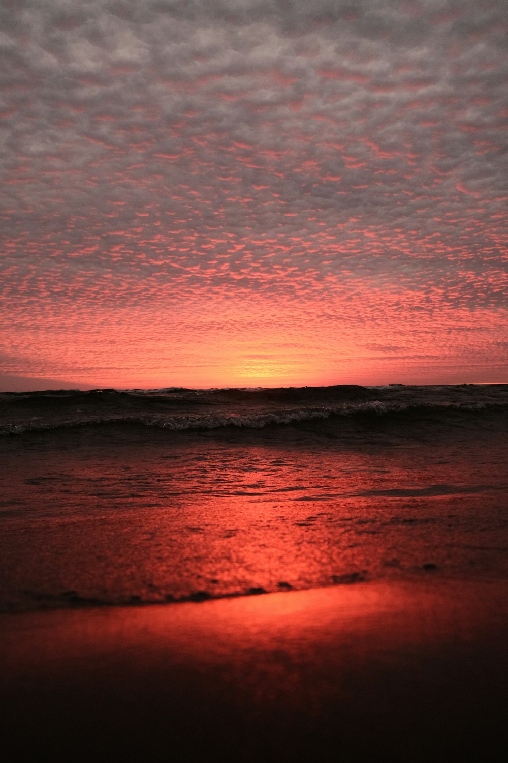 the sun is setting over the ocean on a cloudy day