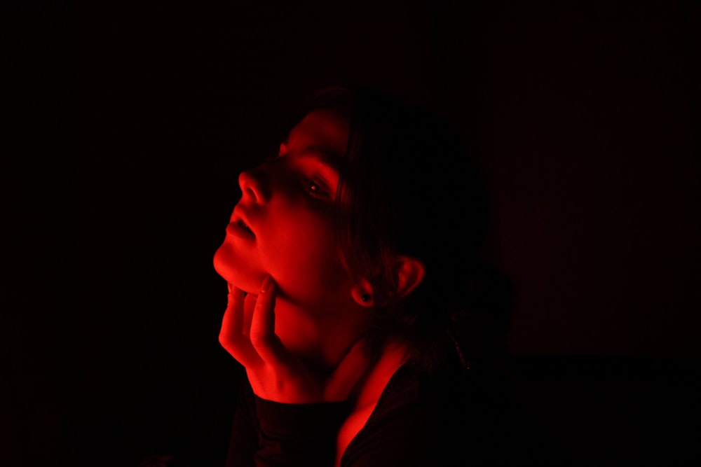 a woman with her hand on her face in the dark
