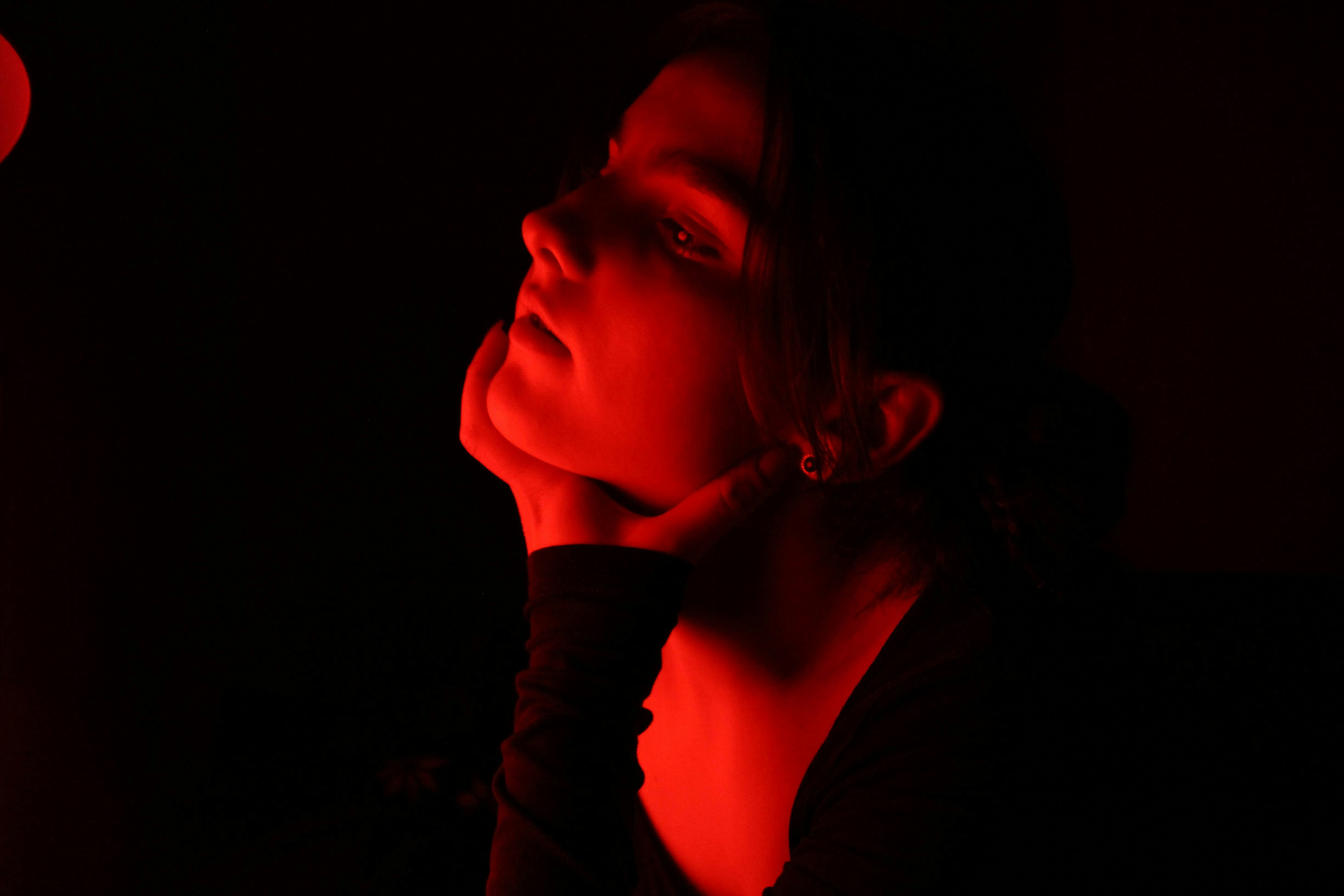 a woman in a dark room with a red light