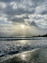 A panoramic ocean sunrise with waves gently rolling onto the sandy shore.