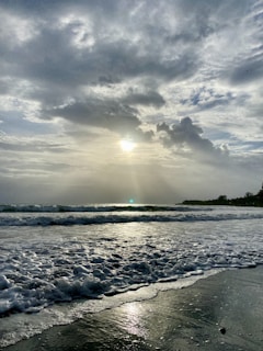 A panoramic ocean sunrise with waves gently rolling onto the sandy shore.