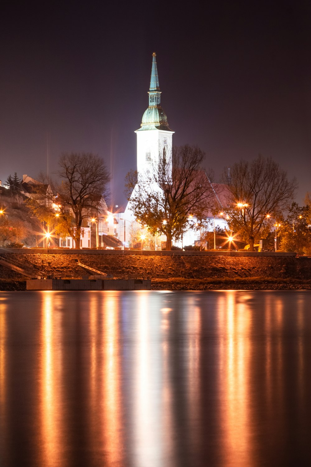 ein großes Gewässer mit einem Glockenturm im Hintergrund