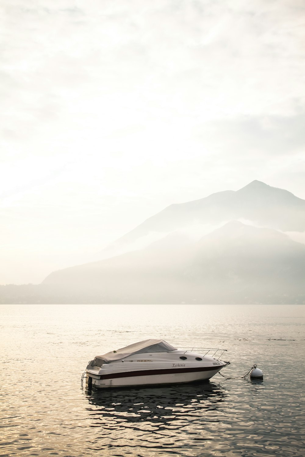 a boat floating on top of a lake next to a mountain