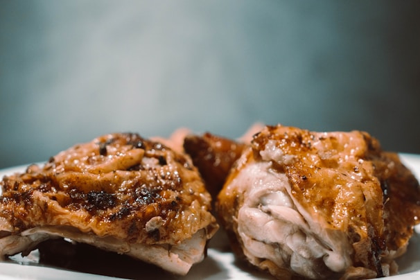 Close-up of a crispy fried chicken piece with steam rising, on a white plate with red accents.