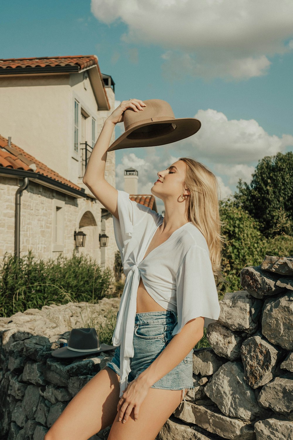 a woman sitting on a stone wall with a hat on her head