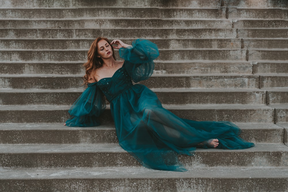 a woman in a blue dress sitting on some steps