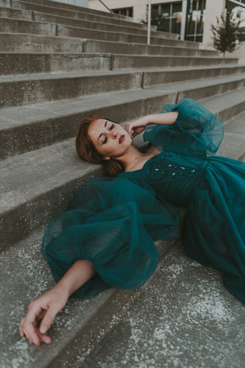 a woman in a green dress laying on some steps