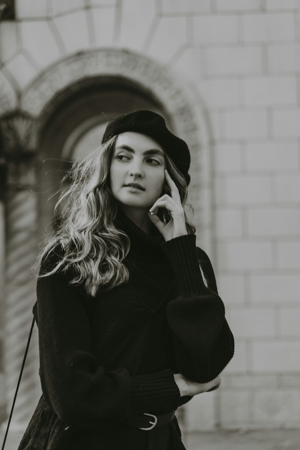 a woman in a black coat and hat talking on a cell phone
