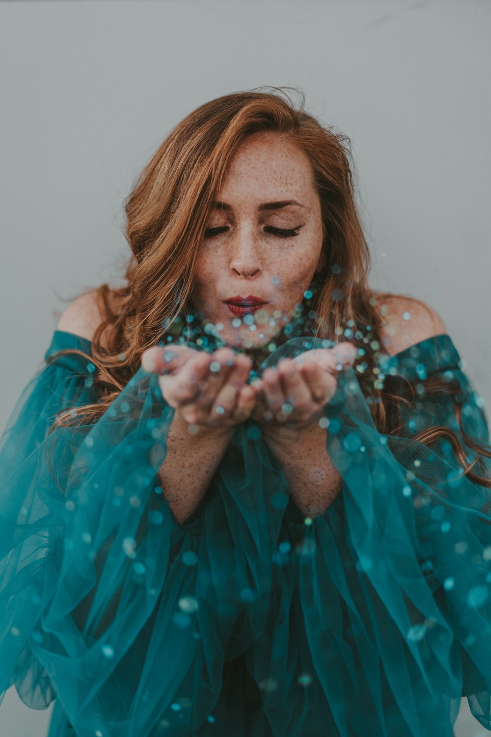 a woman in a blue dress blowing bubbles
