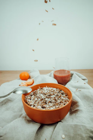 A sleek package of prayo fit crunchy muesli resting beside a glass of fresh orange juice on a bright kitchen counter.