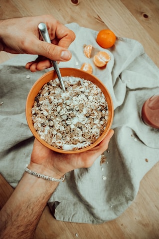 a person holding a bowl of oatmeal next to an orange