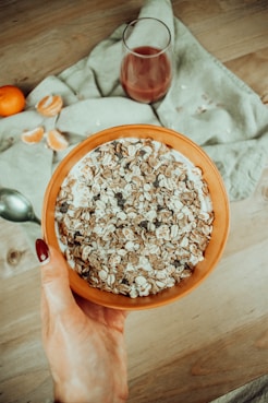 a person holding a bowl of cereal on top of a wooden table