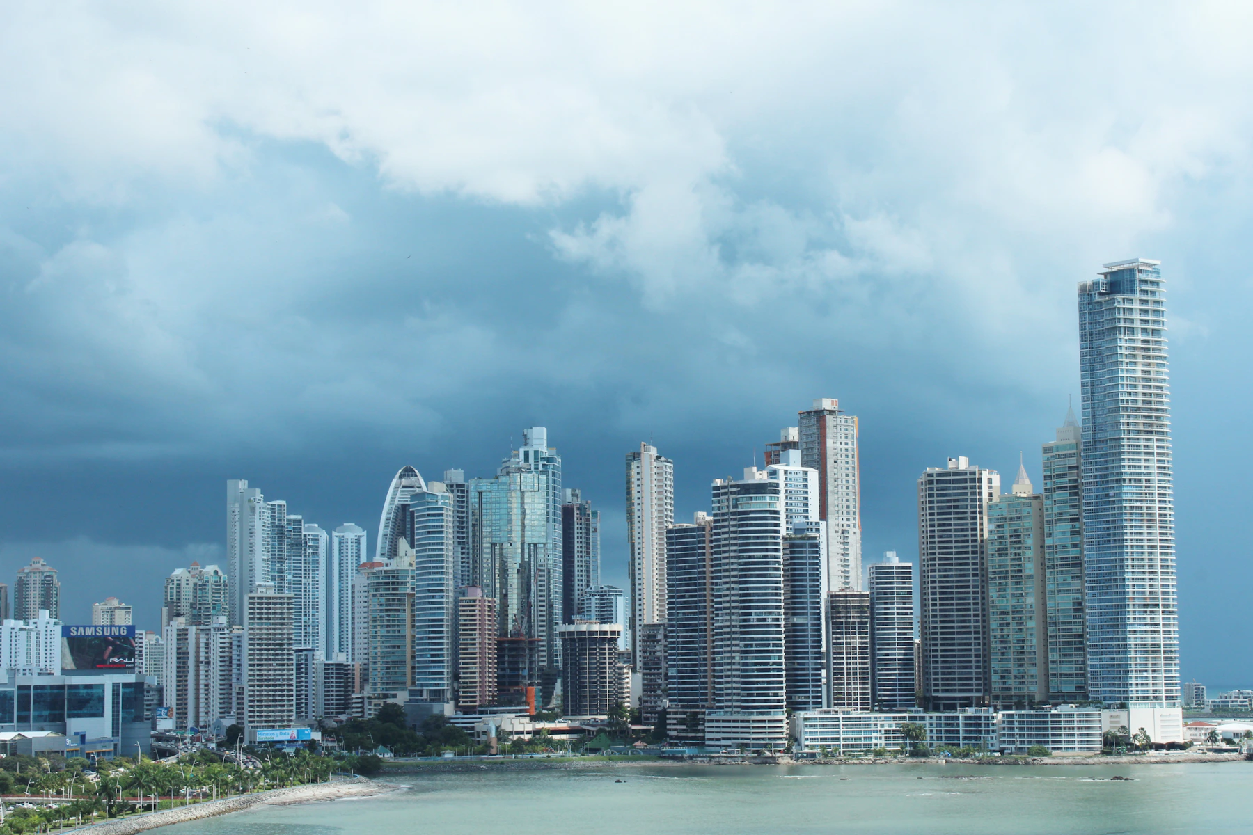 Panama City waterfront towers rising above the bay beneath a cloud-filled tropical sky