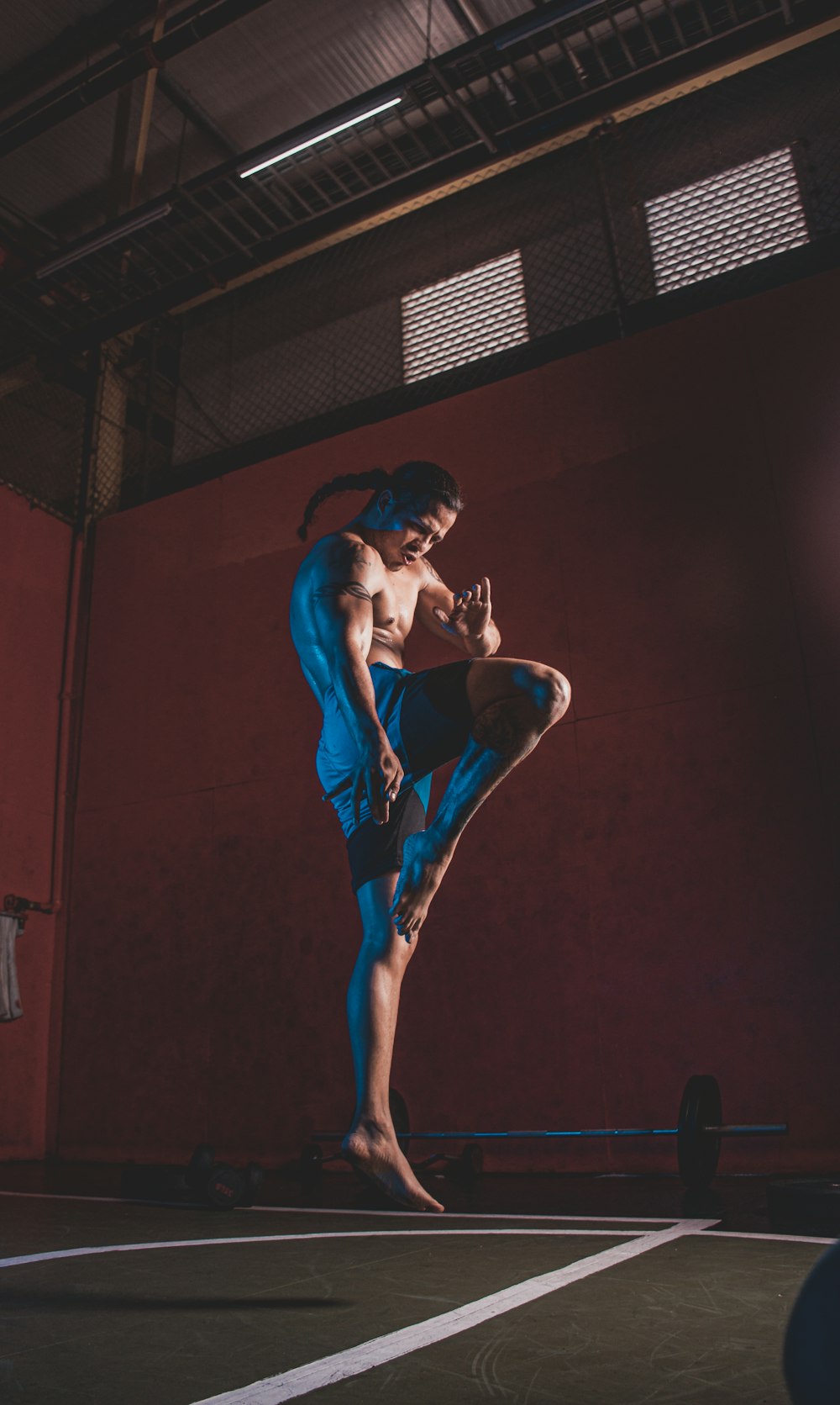 a man standing on one leg in a gym