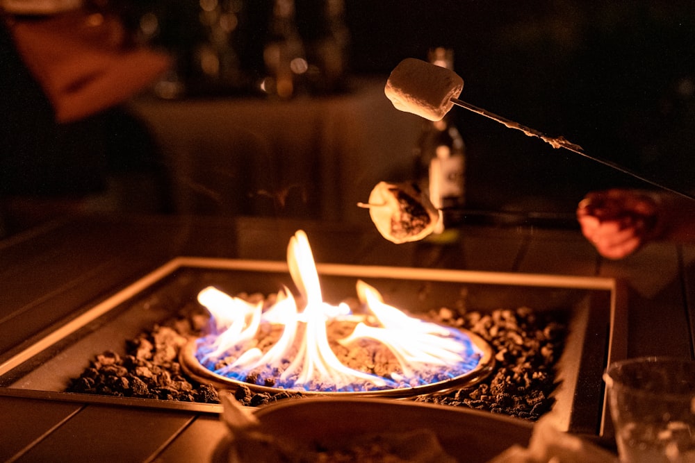 a fire pit with a person cooking food on top of it