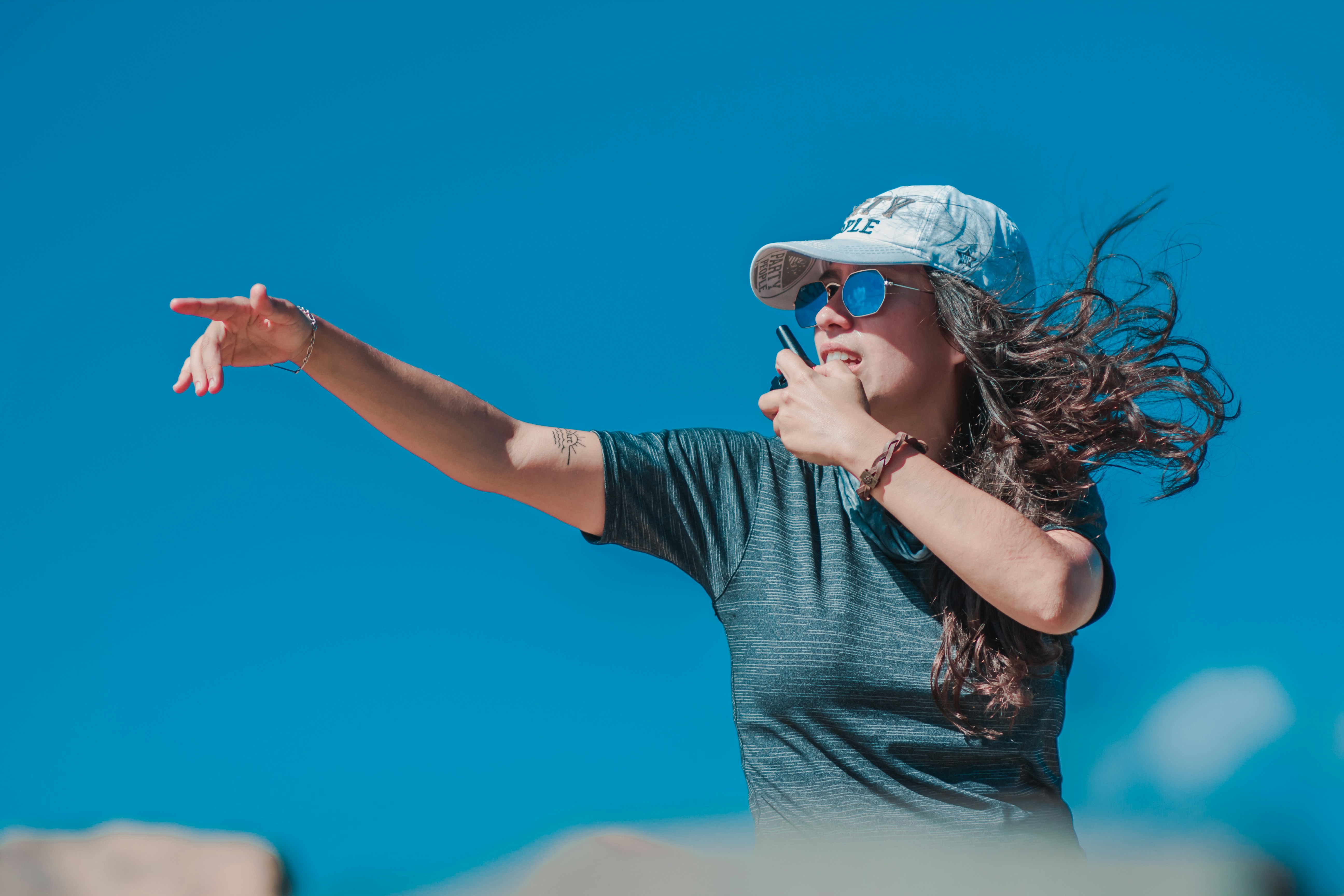 a woman wearing a hat and sunglasses throwing a frisbee